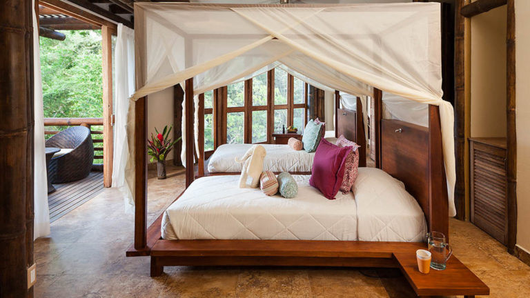 The Superior Suite at La Selva Amazon EcoLodge, a sustainable, luxury accommodation in the Ecuadorian Amazon basin, with a double beds, mosquito nets, and a private balcony with a rainforest view