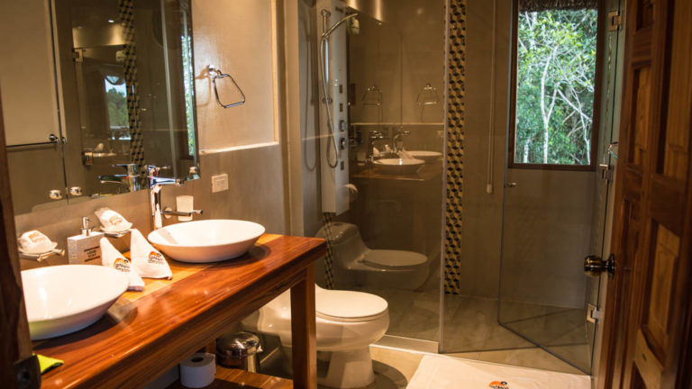 Two sinks and a vanity, with a toilet and a hot shower, inside the bathroom of the Panoramic Suite at the Napo Wildlife Center, a luxury eco lodge surrounded by a rainforest biosphere reserve in the Ecuadorian Amazon.