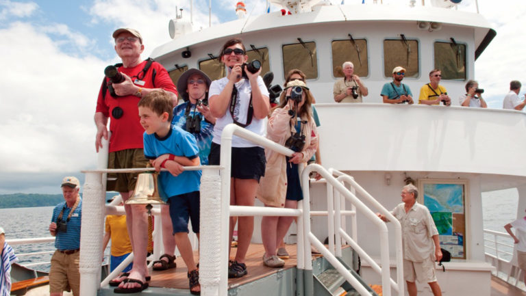 Guests aboard National Geographic Sea Bird expedition ship ready cameras for whale watching