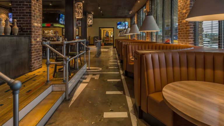 McGivney's Sports Bar and Grill at Four Points Sheraton Juneau hotel, with semicircle booth seating, round wood tables & brick.