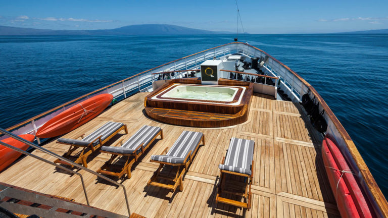 Hot tub, lounge chairs and kayaks off to the side on the bow deck of the small ship Evolution.