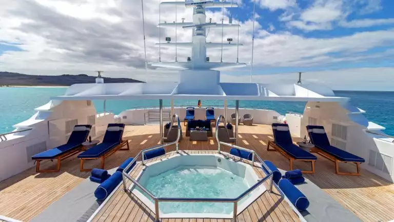 Sun deck of Galapagos Horizon ship with Jacuzzi, chaise loungers with dark blue pads & teak decking.