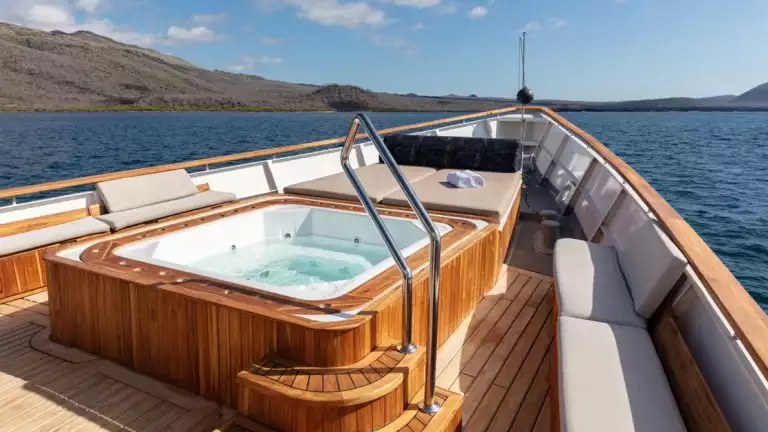 White hot tub with jets on the bow with an expansive view of ocean with lounge seating around tub in Galapagos aboard Grace
