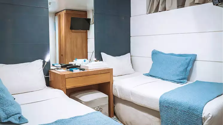 Harmony G yacht Category C stateroom with 2 twin beds, blue and white bedding and nightstand.