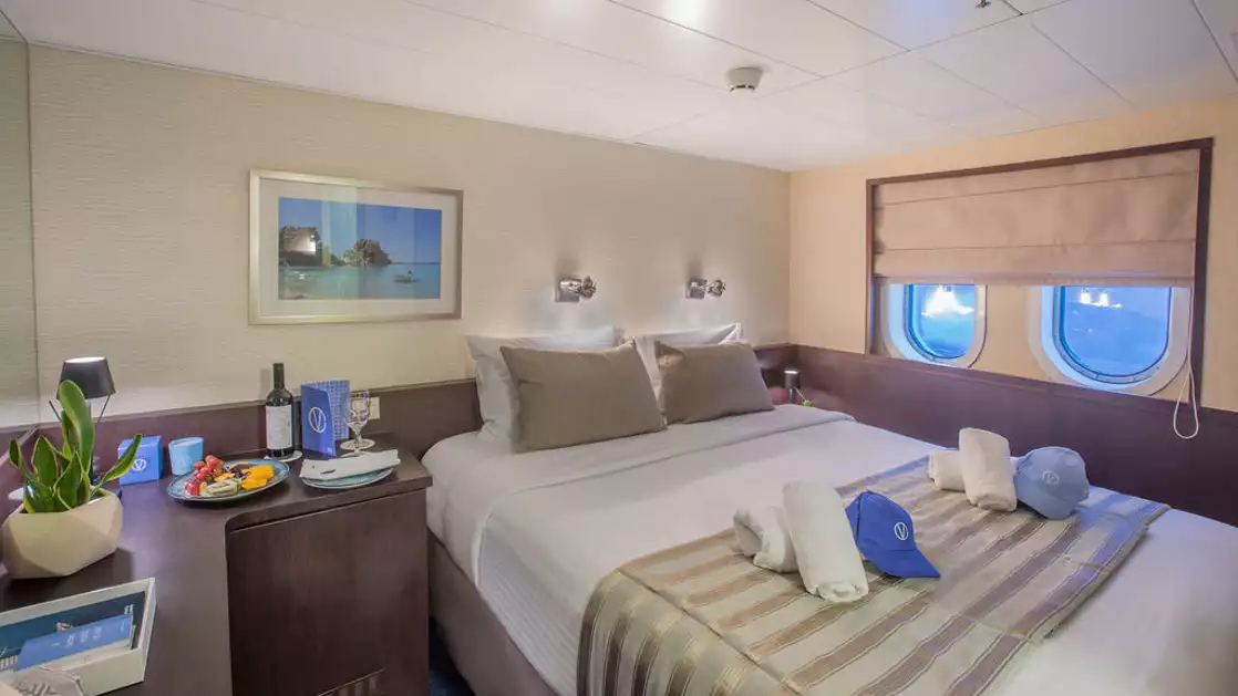 Harmony V yacht Category B stateroom with double bed, 2 windows, desk and reading lights.