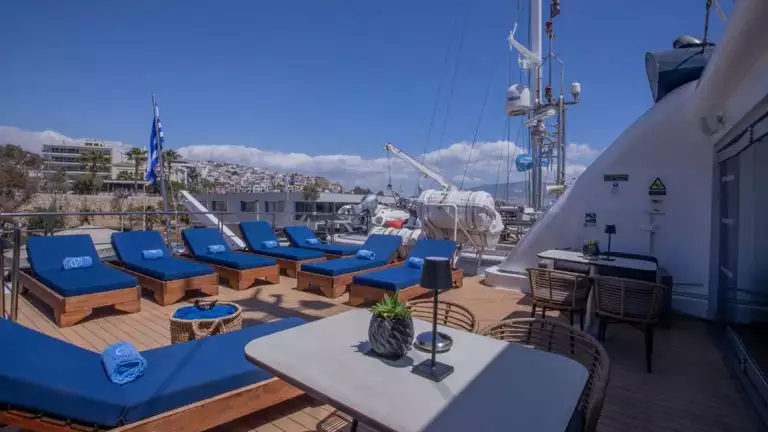 Outdoor sundeck on small cruise ship with blue lounge chairs and blue towels rolled up