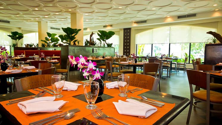 dining room at the holiday inn hotel panama canal with bright orange place mats, flowers on the tables and textured white ceiling