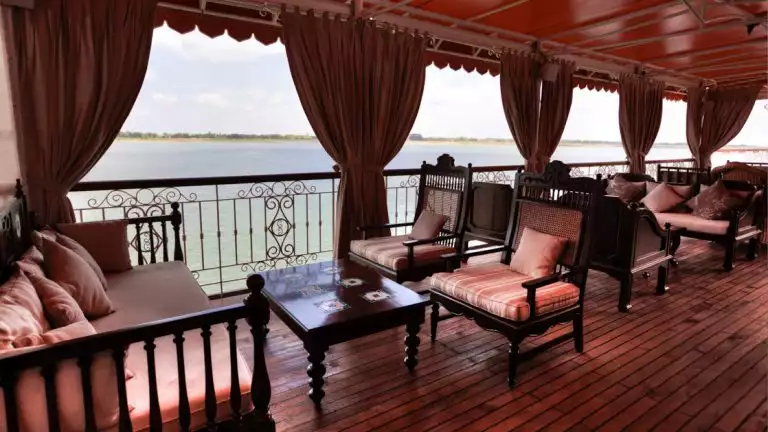 Open air lounge seating with wooden and red couches, chairs and coffee table aboard the Jahan.