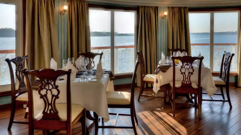 Jahan dining room with floor to ceiling windows, tables and chairs set up for a meal.