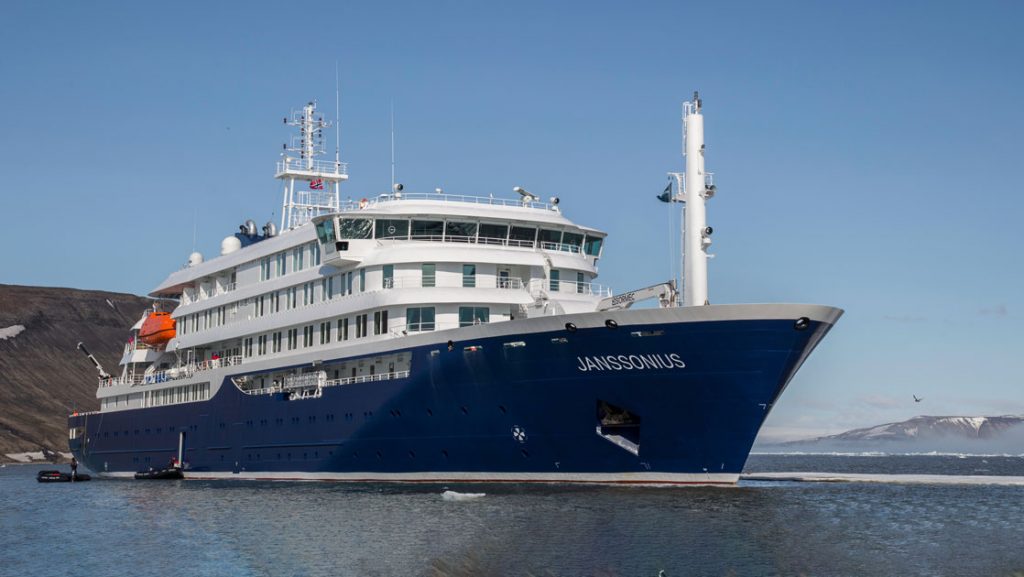 Janssonius polar small ship showing exterior in dark blue lower decks and white upper decks while cruising in icy waters.