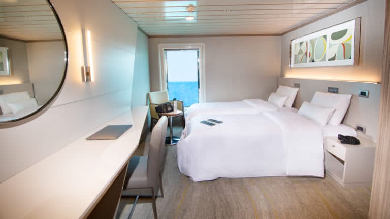 Spacious room aboard the la pinta galapagos with two twin beds, desk and door.