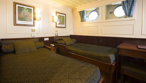 Lord of the Glens Category 1 stateroom with 2 single beds, nightstand, reading lights and 2 portholes.