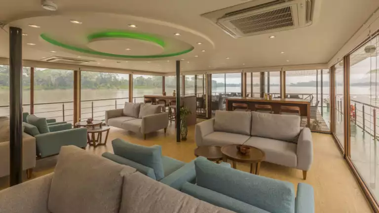 Manatee Amazon Explorer lounge with couches, tables, bar and floor to ceiling windows.