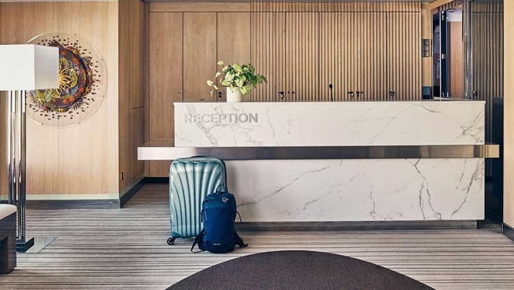 White marble reception desk with wood walls behind & blue luggage in front, on Nat Geo Endurance polar expedition ship.