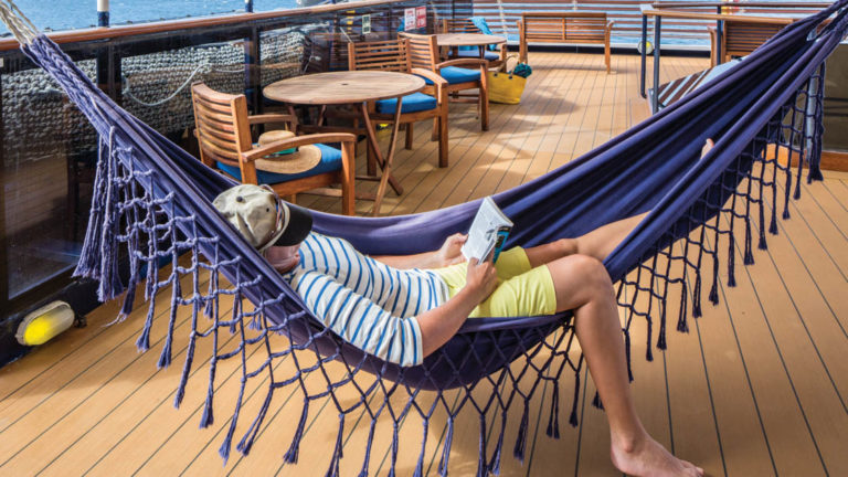 Woman reading in hammock on sunny deck of National Geographic Islander expedition ship in Galapagos Islands