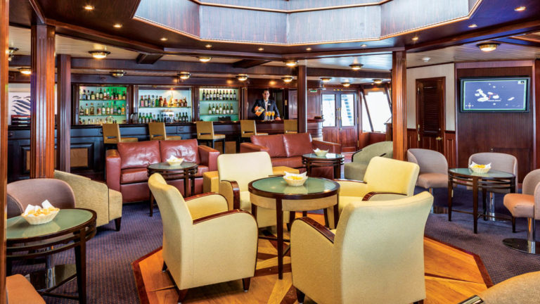 Couches, tables and chairs in lounge and bar aboard National Geographic Islander expedition ship in Galapagos Islands