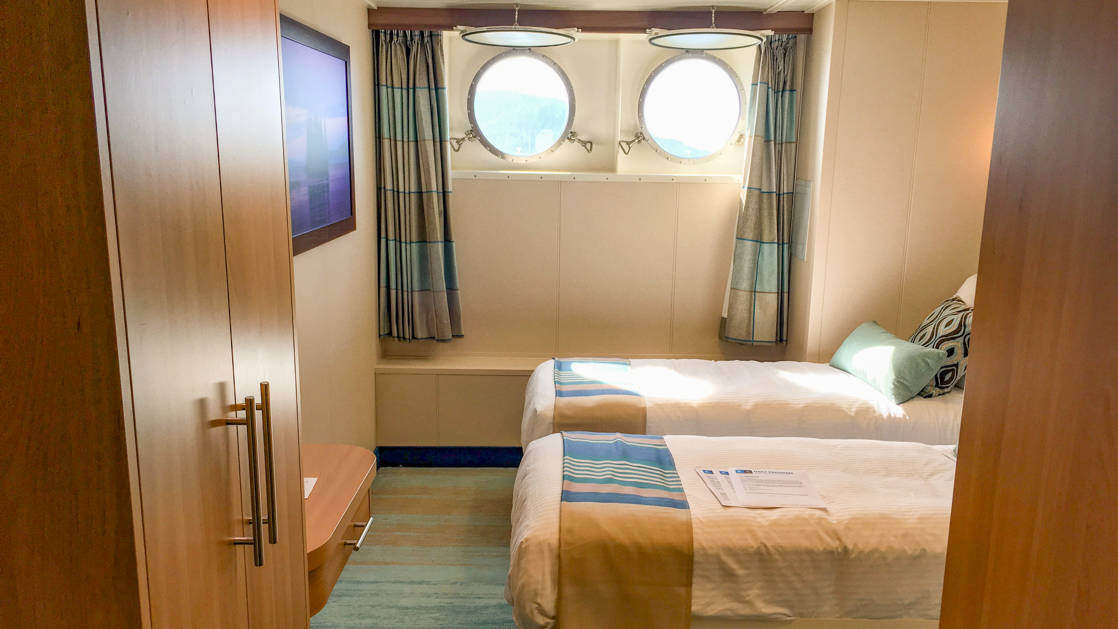 two beds, desk and two portholes in Category 1 cabin aboard National Geographic Quest luxury expedition ship