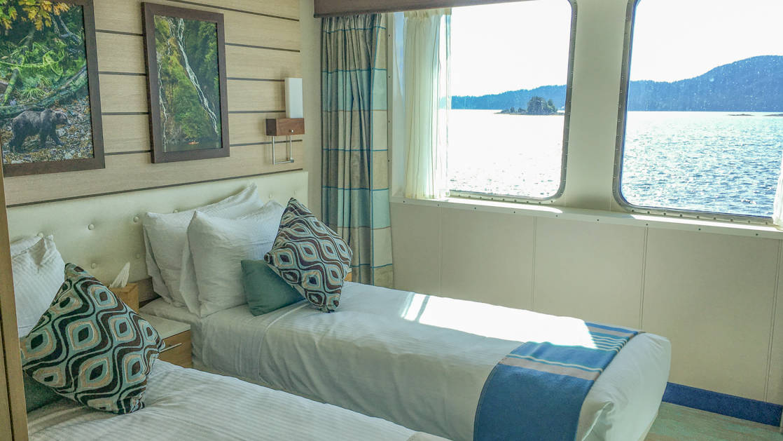 Two beds, nightstand and two large windows in Category 3 cabin aboard National Geographic Quest luxury expedition ship