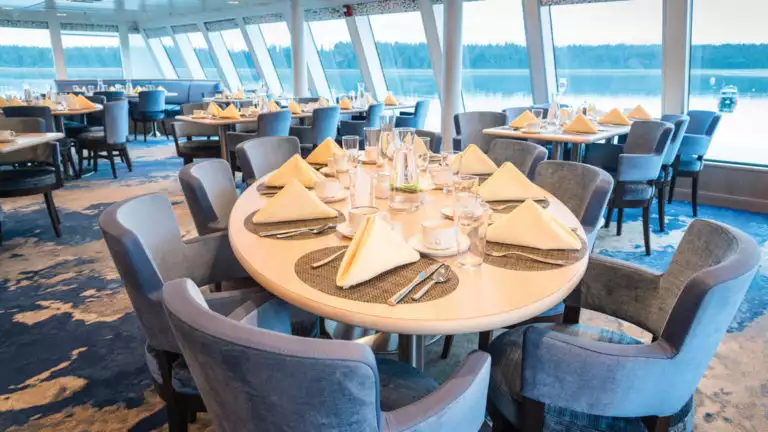 Dining room with elegant table setting and window-lined walls aboard National Geographic Quest luxury expedition ship