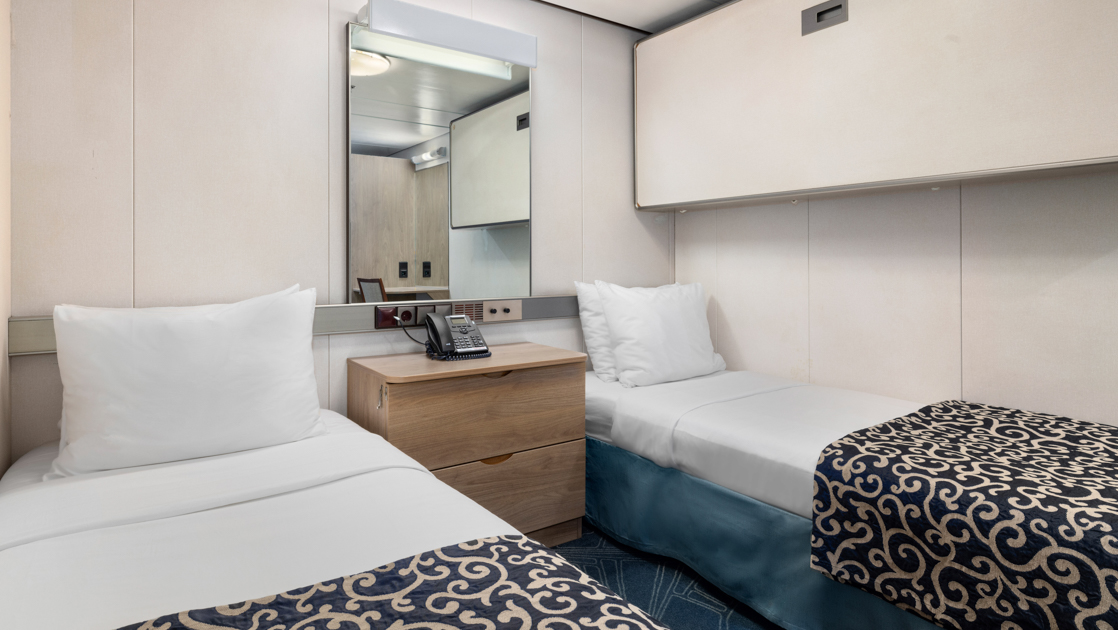 Category 1 Single cabin on Oncean Endeavour with 2 twin beds with white sheets & blue & gold bedding, mirror & no windows.