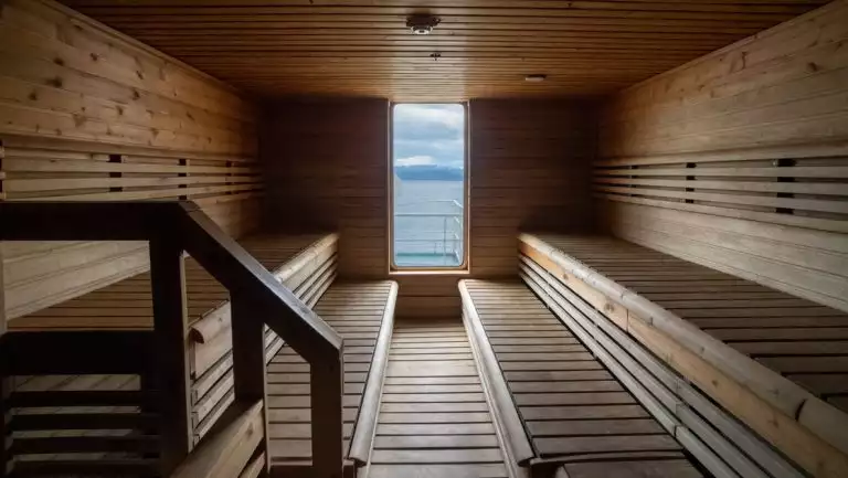 Wooden sauna aboard Ocean Endeavour with 2 long benches & floor-to-ceiling view window.