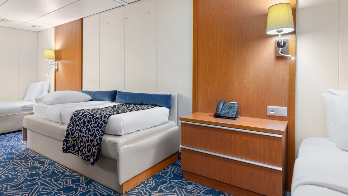Category 2 triple cabin on Ocean Endeavour with 2 twin beds, pull-out couch bed & wood bedside table with lamp.
