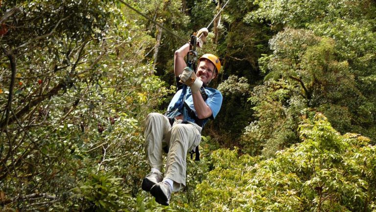a traveler goes on a zip line with the jungle canopy below him on the panama adventure land tour