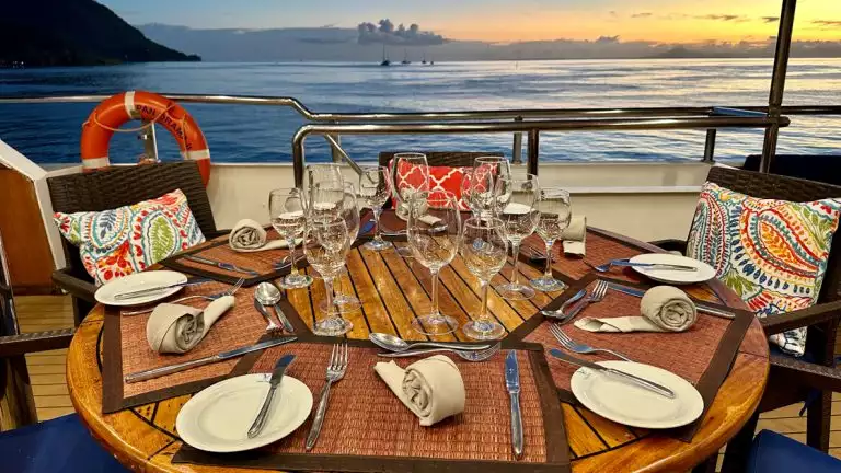 A plated dinner on a small cruise boat overlooking the blue waters and bright sunsets in the background