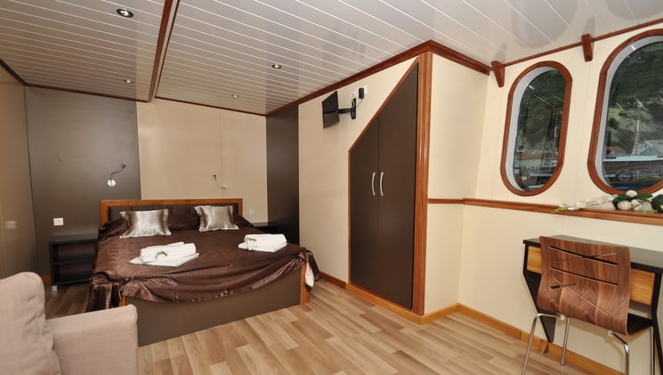 a cabin with wood floors, a bed and an angular door aboard the president mediterranean luxury yacht