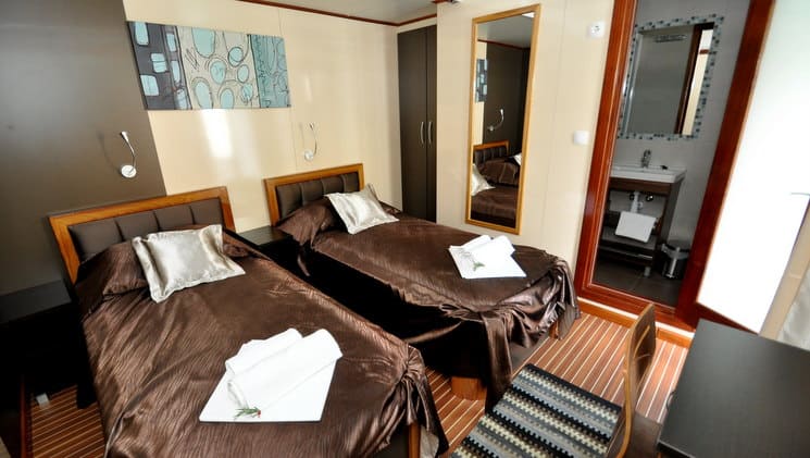 two plush brown beds sitting on hardwood floors and a mirror behind them aboard the president mediterranean luxury yacht