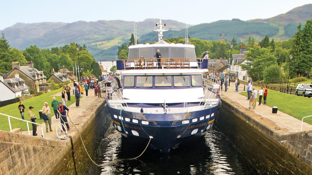 Small ship Lord of the Glens transiting the Caledonia Canal in Scotland with people watching