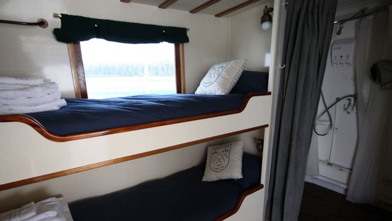 Twin bunk beds, mirror, shower, large view window in Stateroom 5 aboard Sea Wolf yacht in Alaska