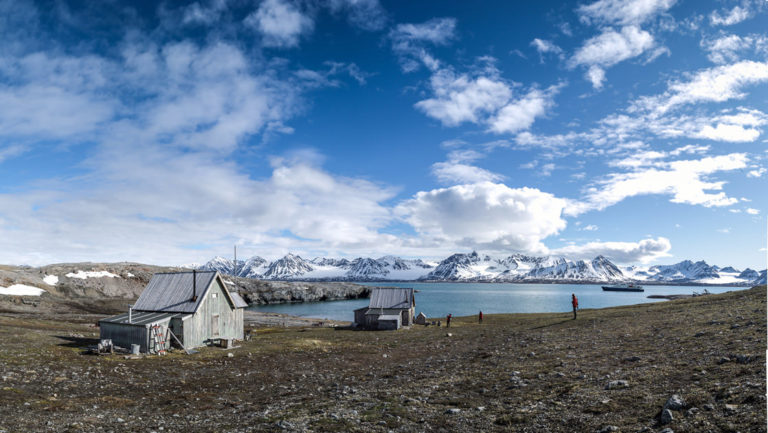 small arctic coastal fishing village on a partly cloudy day with mountains in the distance