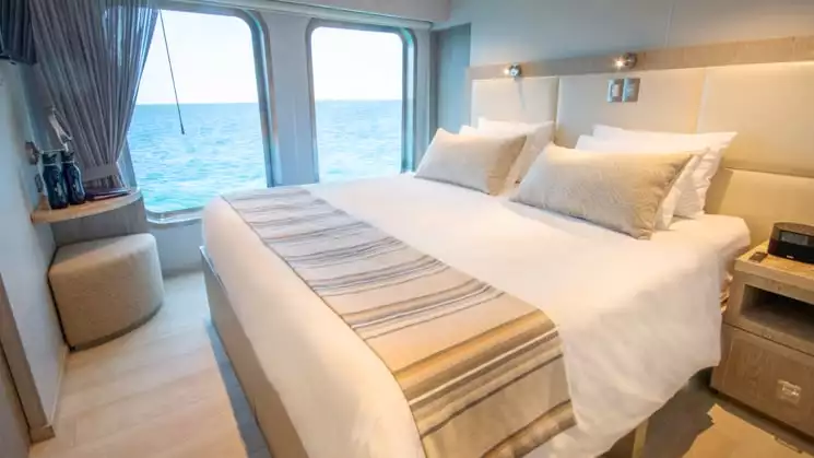 theory luxury small ship cabin with king bed and large window looking out at the ocean