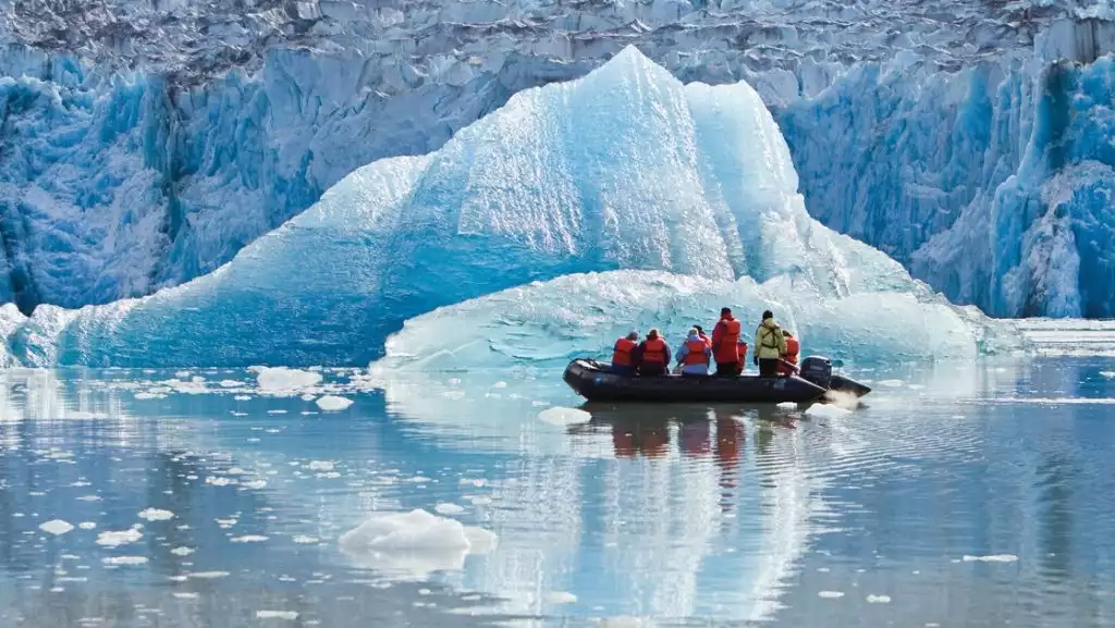Zodiac dinghy with Treasures of the Inside Passage: Alaska & British Columbia cruise guests motors past a massive piece of glacier ice.