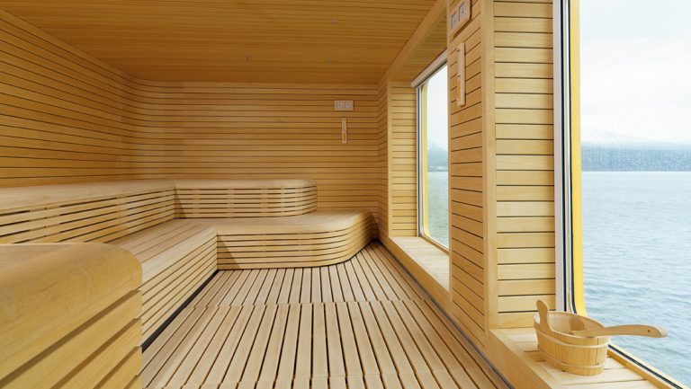 Wood sauna aboard Ultramarine ship, with long wraparound bench, water bucket & a large window revealing polar seascapes.