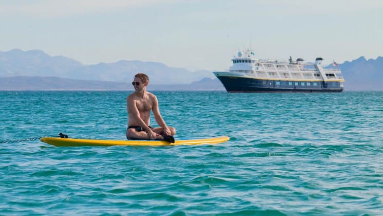 man on paddleboard off port bow of wild california escape: channel islands cruise ship