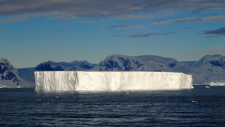 The cap of an iceberg rises above the sea water in antarctica as part of the polar circle cruise