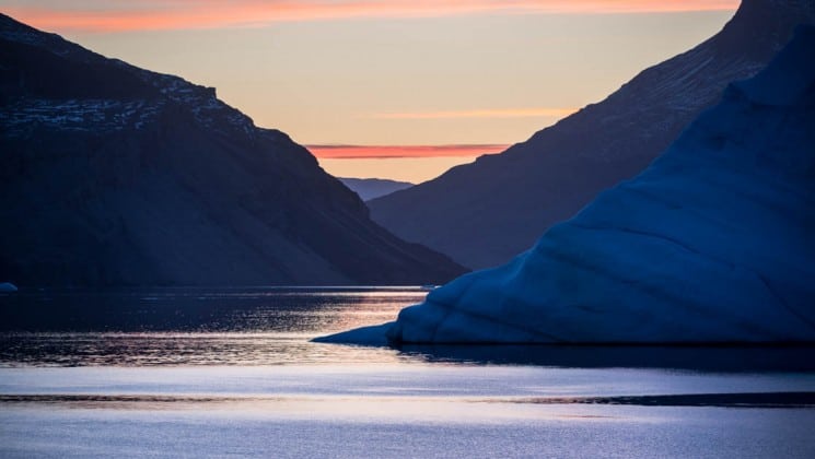 a sunset silhouettes fjords in the ocean in the arctic circle near spitsbergen
