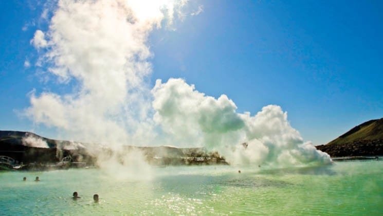 steam rises from a blue lagoon and geothermal hot springs in iceland