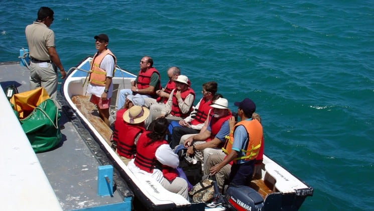 Passengers in life jackets board a small boat to travel back to the Grace yacht, after a day of visiting wildlife and exploring the Galapagos islands