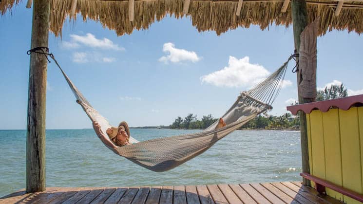 A traveler relaxing in a hammock on a dock with a grass shade.