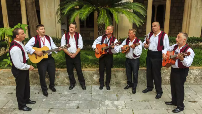 A group of Klapa Singers & musicians in black pants, white shirts & red vests, seen on the Croatia Under Sail small ship cruise.