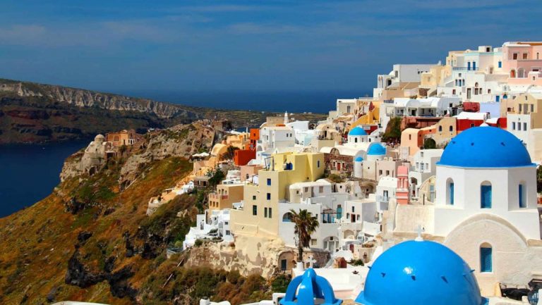 The view of santorini's blue domes and white architecture along the bluffs above the mediterranean as seen from the small ship cruise sailing the greek isles