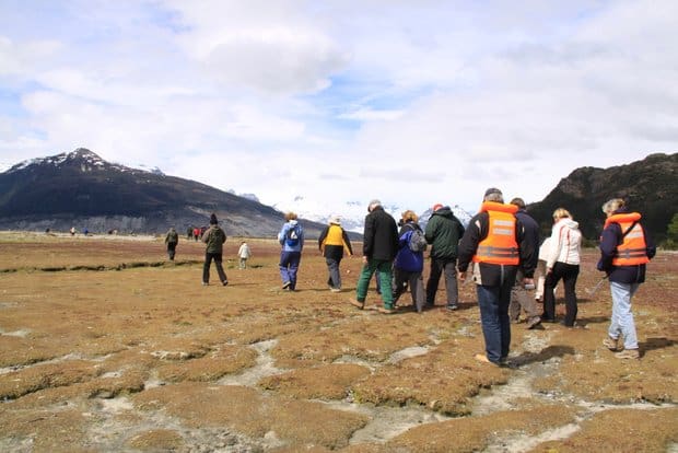 Group of Patagonia travelers hiking on tidal flats with mountains.