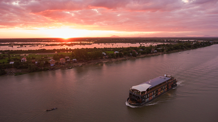 Aerial of river cruise ship Aqua Mekong cruising on Tonle Sap river at sunset, Kampong Tralach, Kampong Chhnang, Cambodia