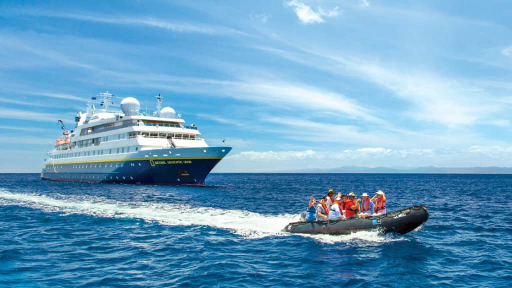 Guests on Zodiac in front of the National Geographic Orion small ship in Fiji, South Pacific on a sunny day
