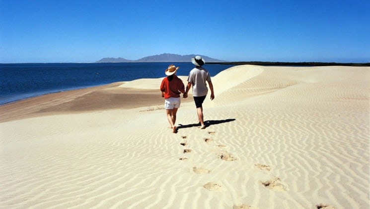 couple walking on beach during shore excursion on baja: a remarkable journey cruise