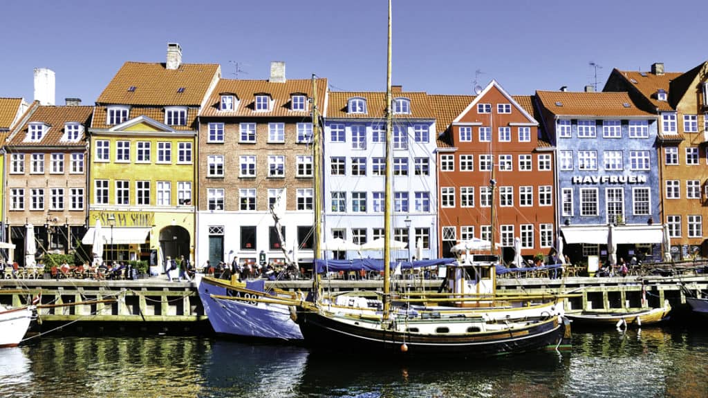 Colorful buildings in Nyhavn along the Waterfront in Copenhagen with several small ships in front