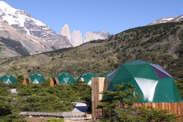 Eco tents lined across a valley floor with mountains and rock spires.